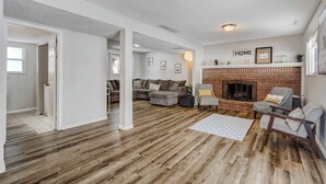 Een ruime woonkamer met een open haard, houten vloeren en een gezellige zithoek.