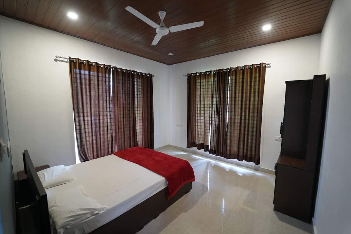 A bedroom with two beds, a ceiling fan, and curtains.