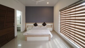 A bedroom with a large bed, two bedside tables, a ceiling fan, and a window with blinds. - HIMANI HERITAGE (Madikeri)