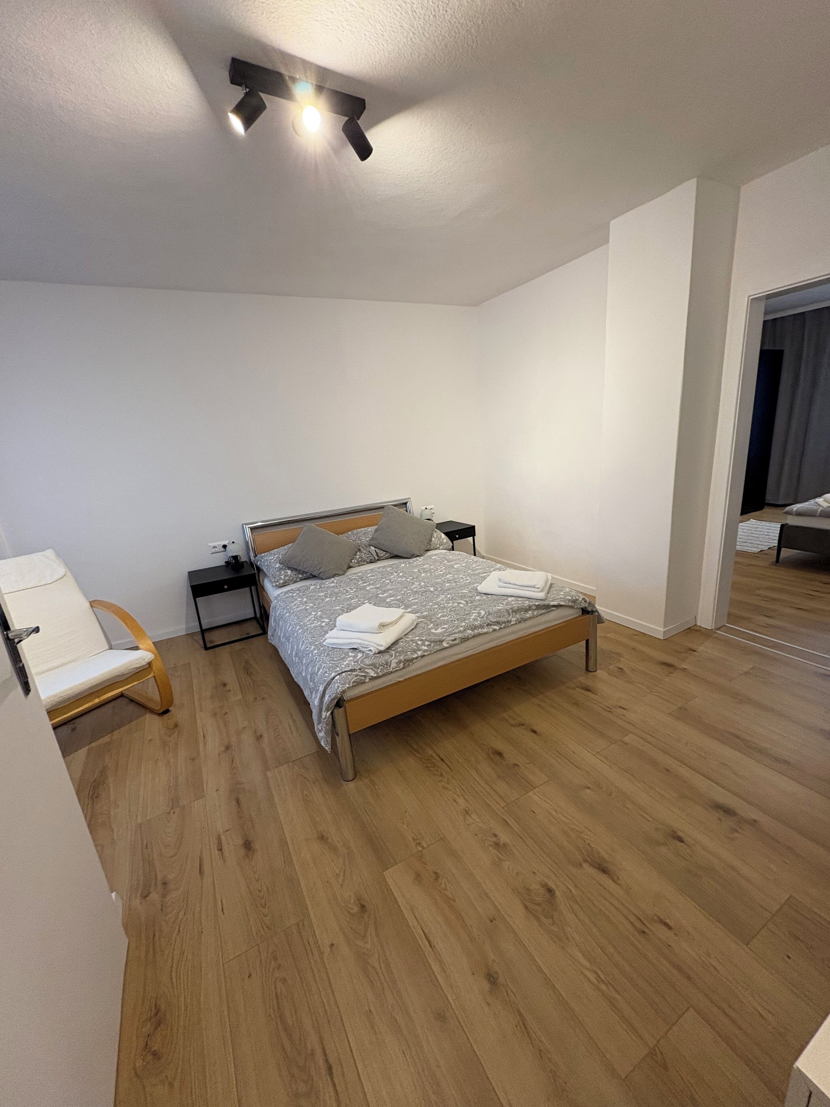 Une chambre à coucher comprenant un lit, des tables de chevet, une chaise et un luminaire au plafond.