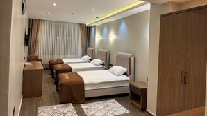A hotel room with two beds, a desk, a wardrobe, and a bathroom. - Aydoğanlar Otel (Emirdag)