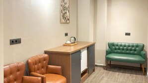 A modern room with a wooden desk, two leather chairs, a green sofa, a clock, and a framed artwork on the wall. - Aydoğanlar Otel (Emirdag)