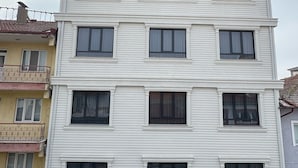 A multi-story building with a white facade, multiple windows, and balconies. There are signs for 'AYDOGANLAR HOTEL' and 'Carrefour'. - Aydoğanlar Otel (Emirdag)