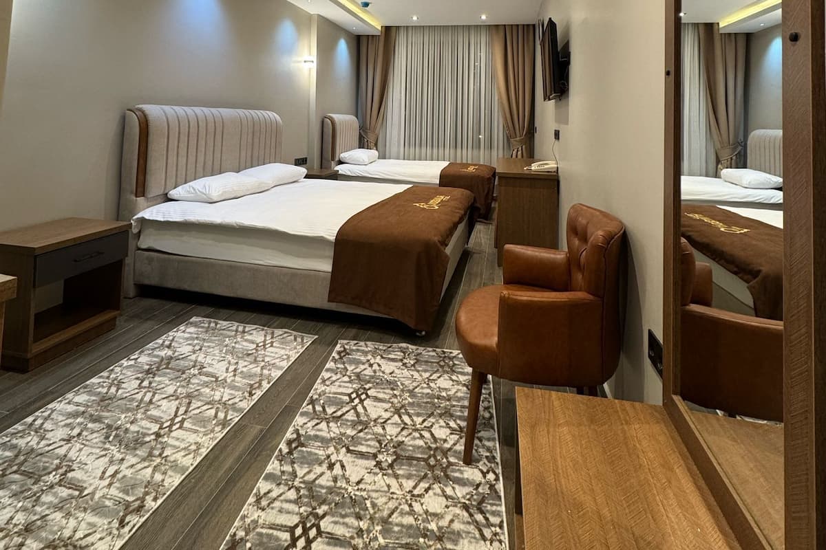 Una habitación de hotel moderna con una cama grande, un escritorio, una silla, un espejo y una alfombra estampada.