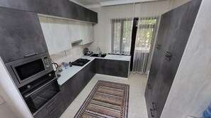 A modern kitchen with dark cabinetry, a built-in microwave, and a gas stove.