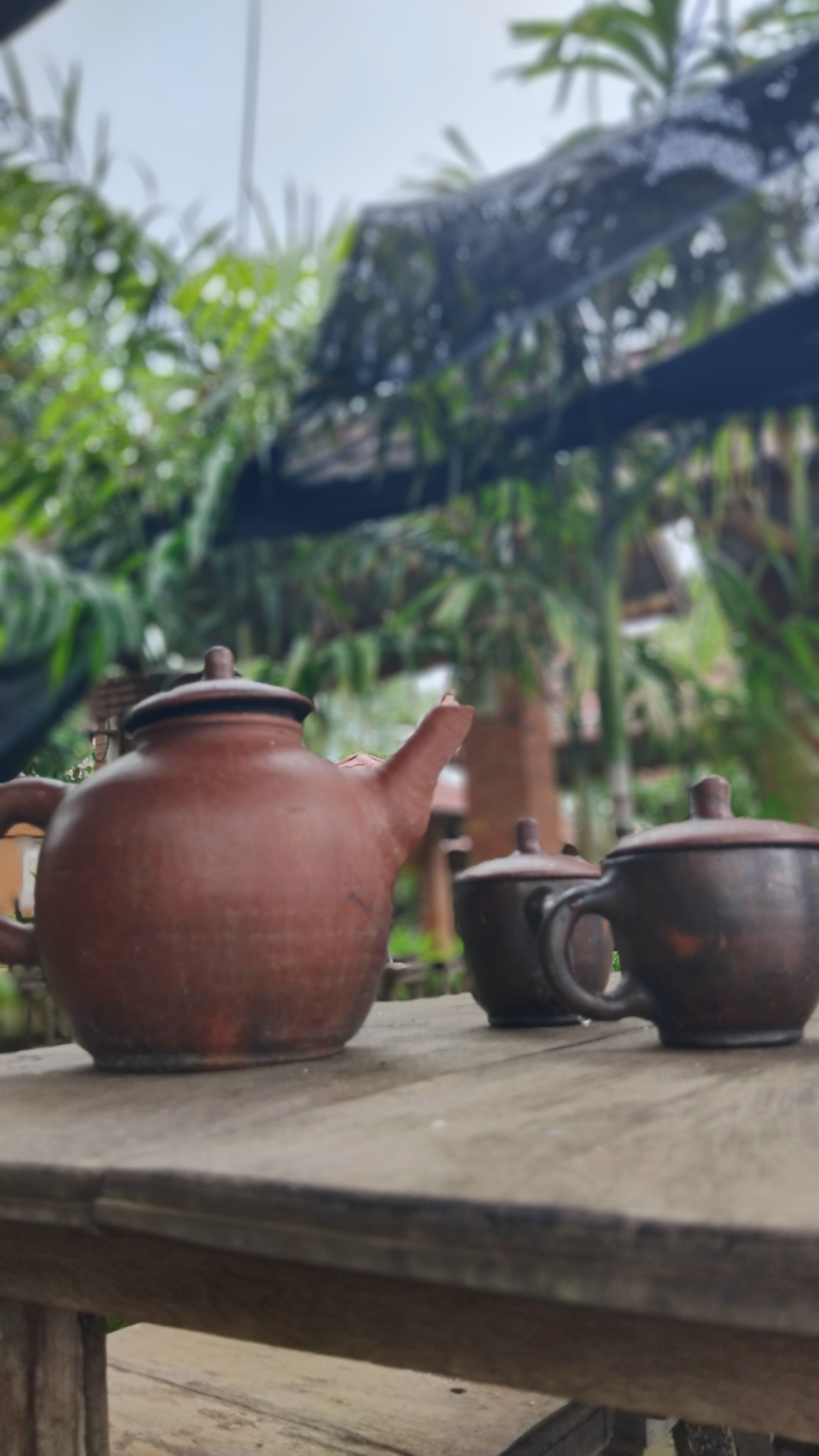 A rustic wooden table with a clay teapot and a matching cup.