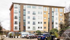 A multi-story residential building with a parking area in front.
