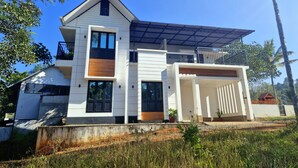 A modern two-story house with a flat roof, large windows, and a balcony. - Scenic Mansion  Munnar (Anachal)