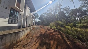 A modern building with a concrete pathway leading to a gated entrance. - Scenic Mansion  Munnar (Anachal)