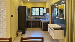 A compact kitchen with a built-in sink, a window, and a mirror above the sink. - Scenic Mansion  Munnar (Anachal)