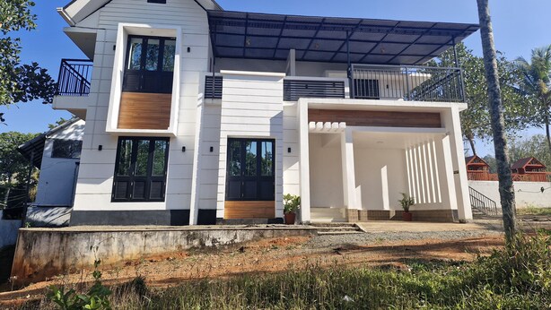 A modern two-story house with a flat roof, large windows, and a covered porch. - Scenic Mansion  Munnar (Anachal)