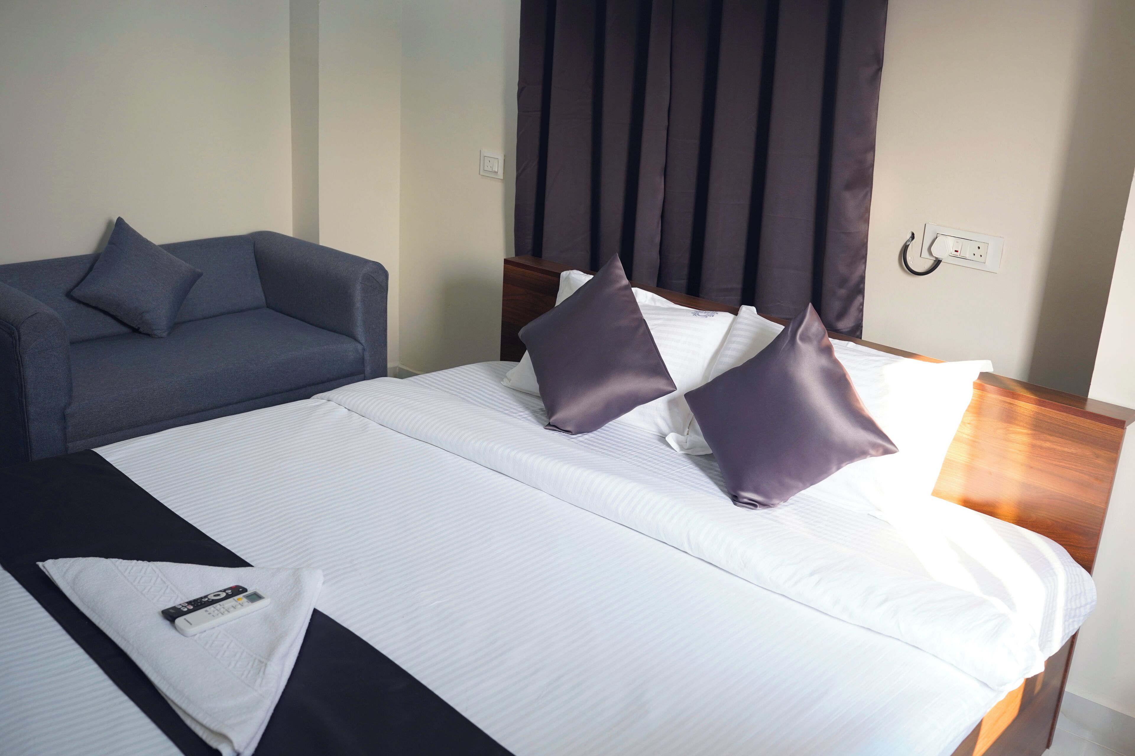 A hotel room with a bed, a sofa, and a nightstand.