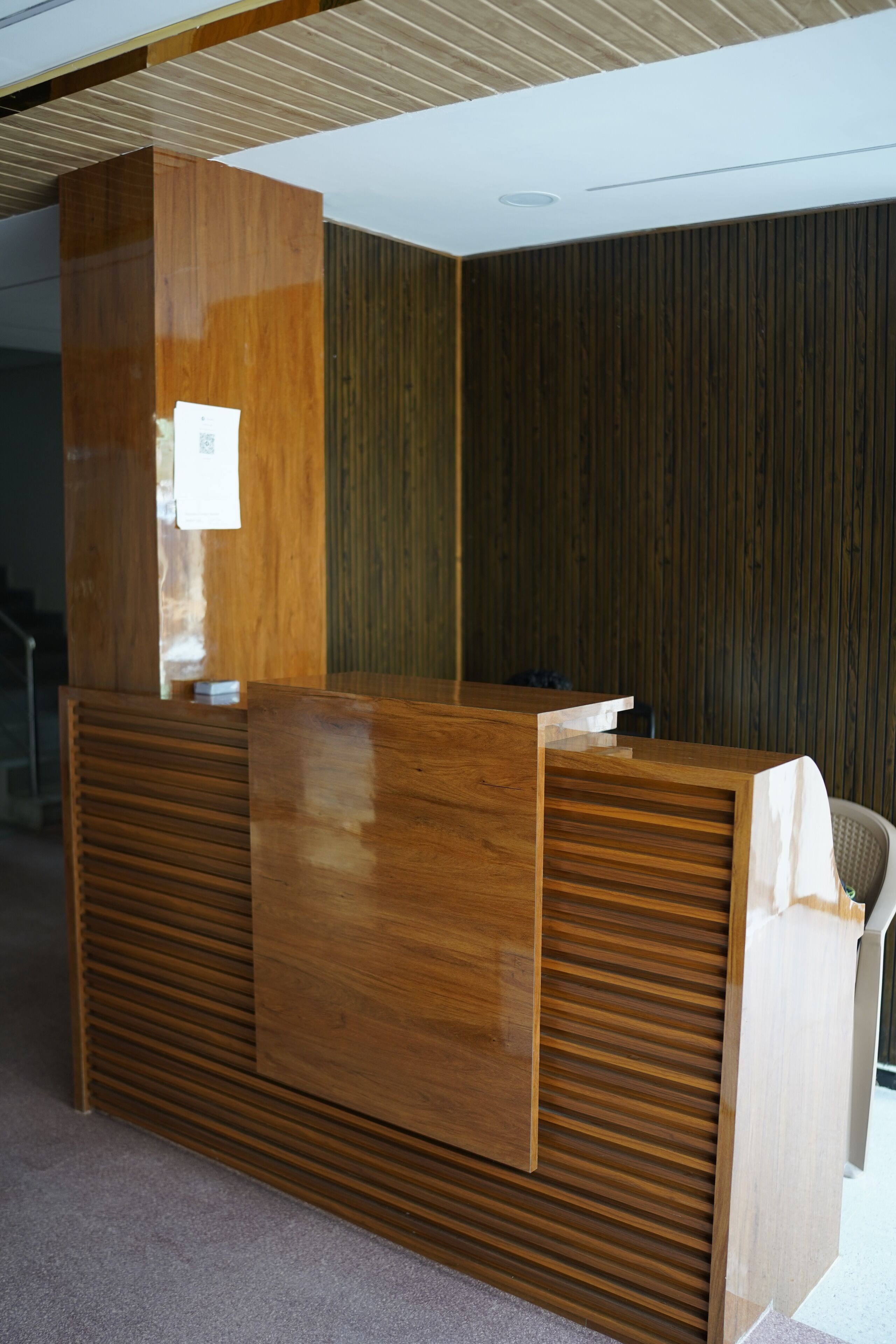 A reception desk with a wooden finish and a vertical panel design.