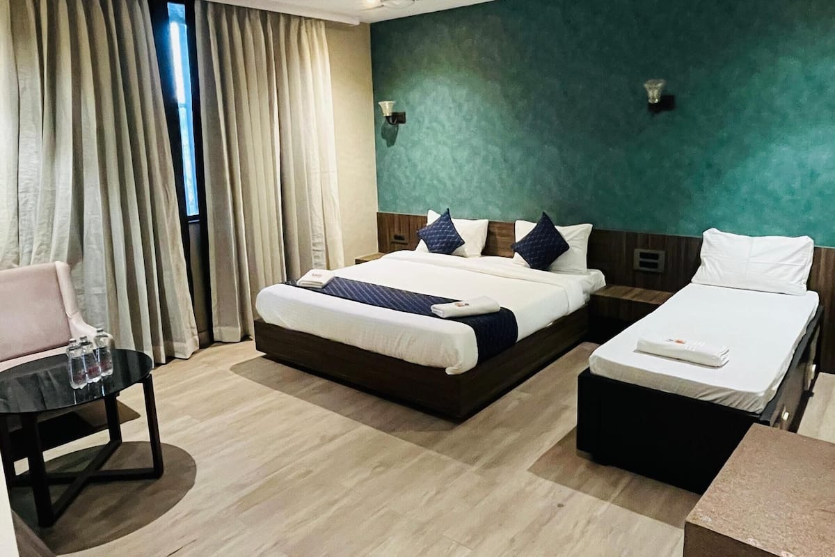 A hotel room with a bed, a desk, a chair, and a small table.