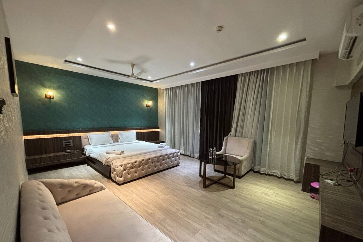 A modern hotel room with a large bed, a sofa, a small table, and a TV.