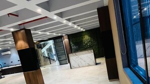 A spacious lobby with a marble floor, a modern ceiling design, and a large window with a view of the outdoors. - Hotel Elegant inn- Ichhapore (Surat)