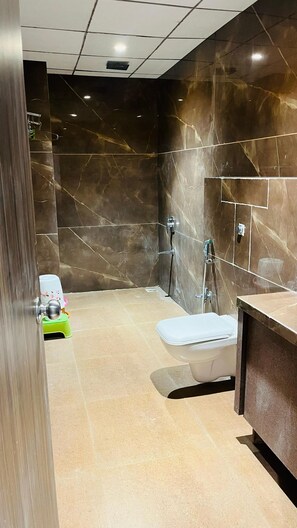 Une salle de bain moderne avec un mur en marbre, des toilettes, une douche et un lavabo.