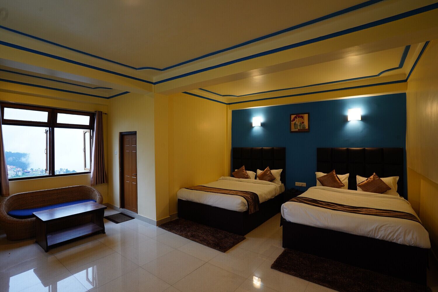 A hotel room with two beds, a sofa, and a window with a view.
