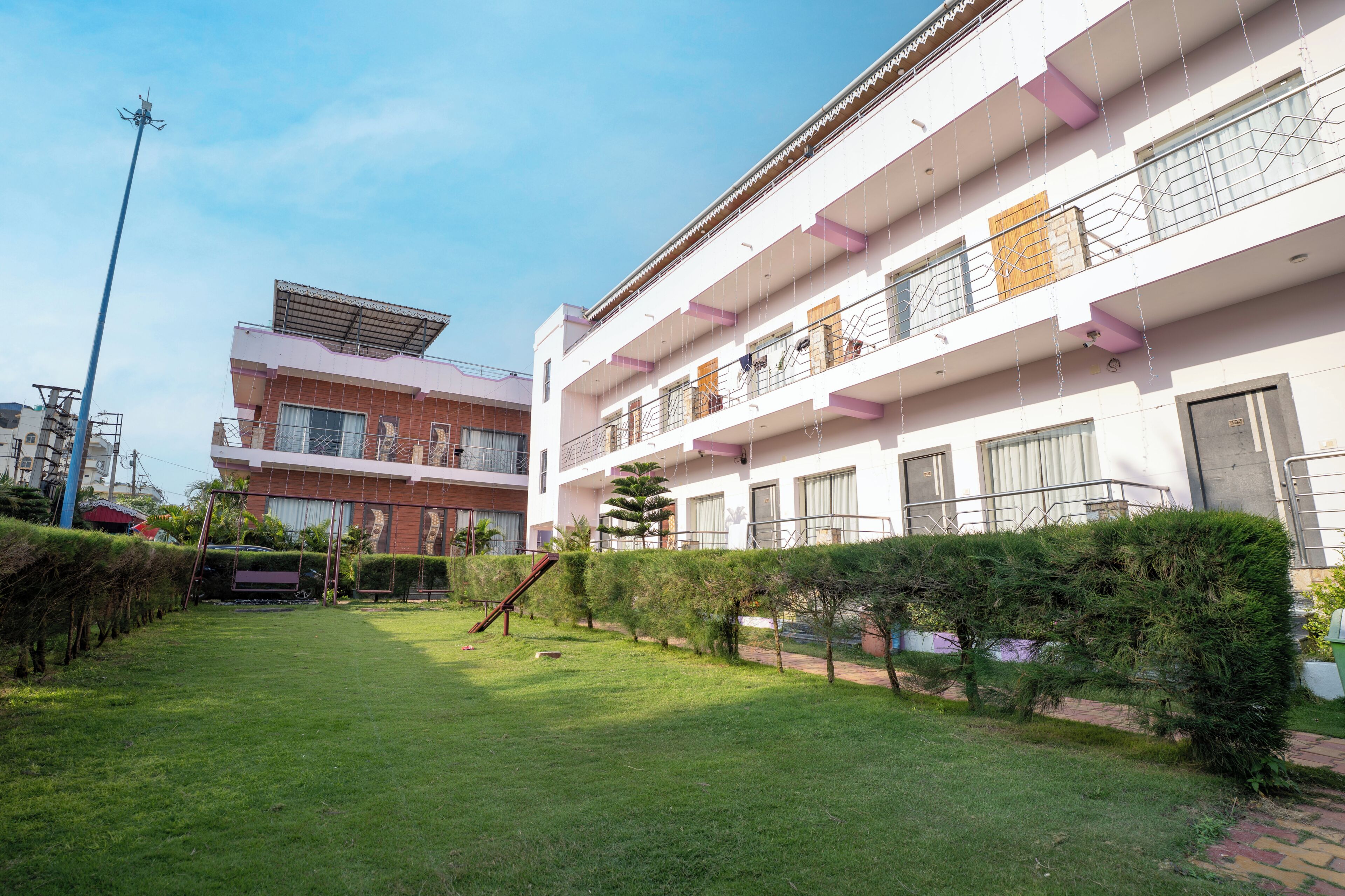 A courtyard with a grassy area, a swing set, and a building with balconies and windows.