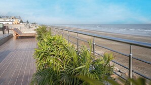 A wooden deck with a metal railing overlooking a beach.