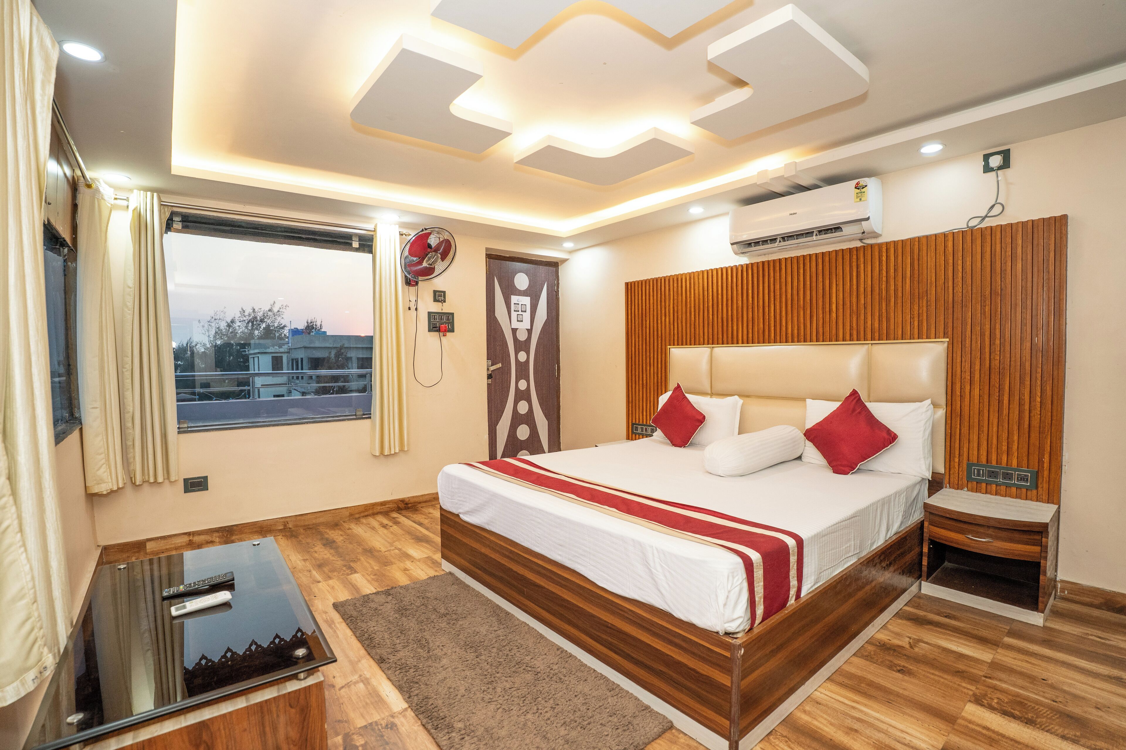 A modern bedroom with a large bed, wooden paneling, and a view of the cityscape.