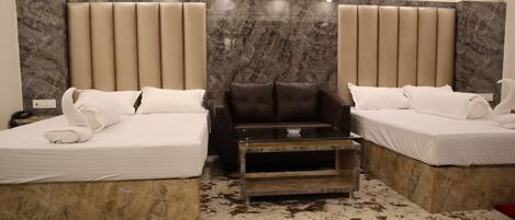 A hotel room with two beds, a sofa, and a small table.