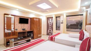A hotel room with two beds, a TV, a wooden wardrobe, and a window with curtains.