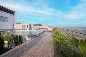 A rooftop pool area with a view of the beach, a stone structure, and potted plants. - Mandarmani Kiss of Sea Resort (Kanthi)