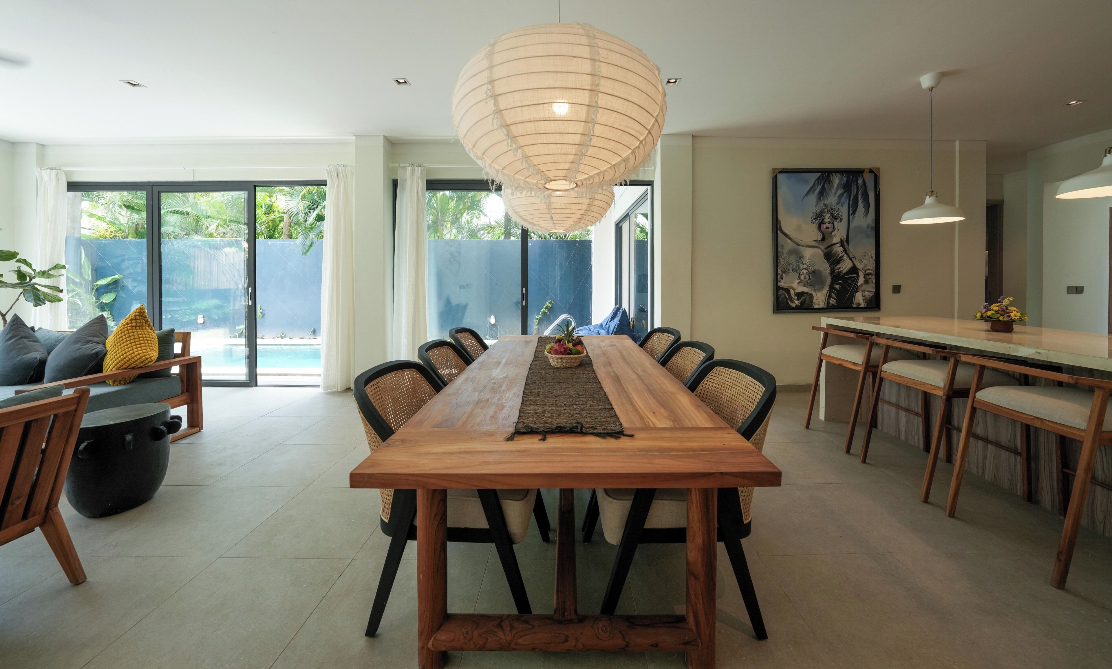 Un comedor amplio con una larga mesa de madera, rodeada de sillas y una lámpara colgante.