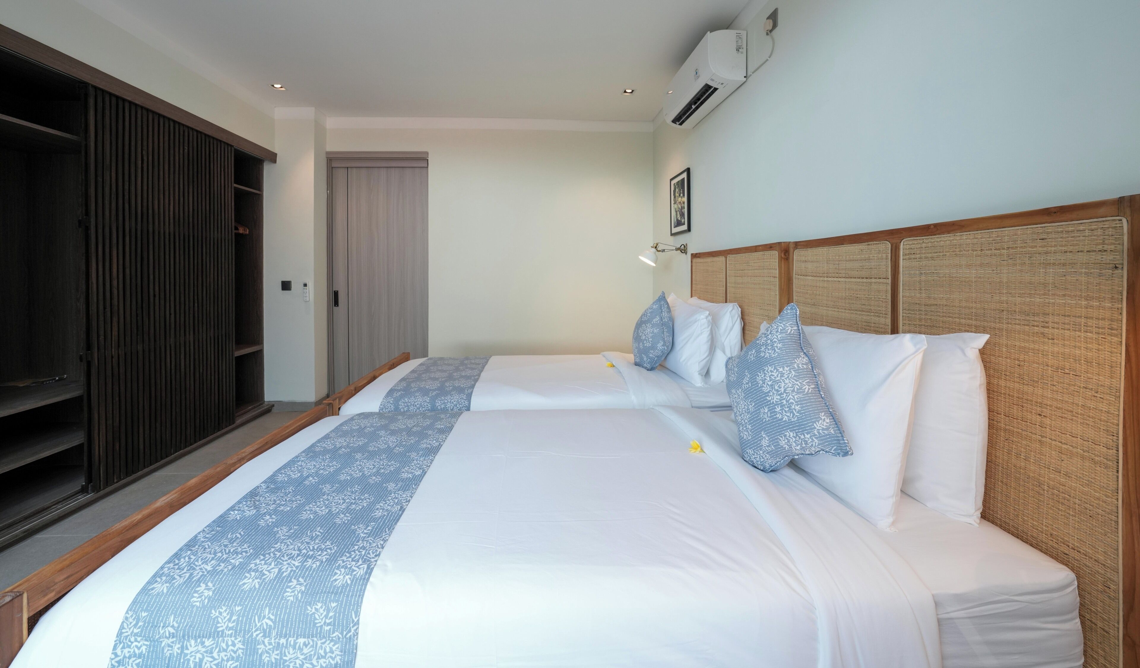Habitación de hotel con dos camas, un armario y un equipo de aire acondicionado.