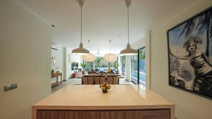 Una cocina moderna con iluminación colgante, una isla central y un cuadro grande en la pared.