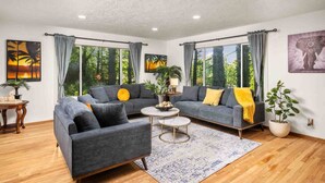 A living room with a grey sofa set, a round coffee table, and a blue patterned rug. - Wonderful Forested Retreat, Hot Tub, Pet Friendly, Game Room, Pool Table, Fire-Pit, on 2 Acres (Gresham)