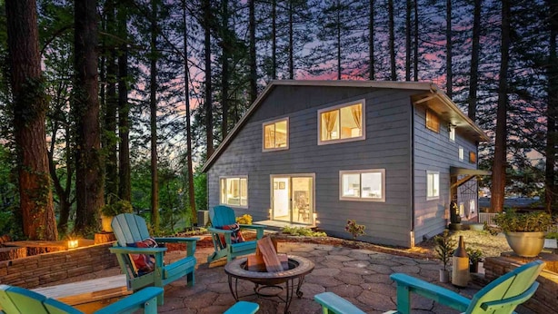A two-story cabin with a stone patio, outdoor seating, and a fire pit. - Wonderful Forested Retreat, Hot Tub, Pet Friendly, Game Room, Pool Table, Fire-Pit, on 2 Acres (Gresham)