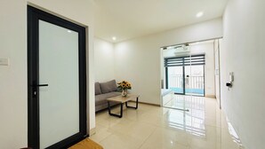 A modern living room with a sofa, a coffee table, and a vase of flowers. - Era Apartment Dinh Thon (Hanoi)