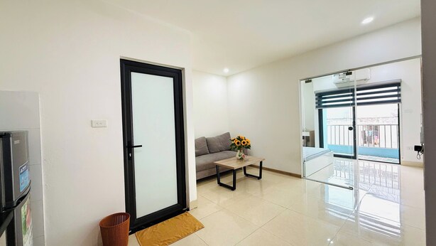 A modern living room with a sofa, a coffee table, and a vase of flowers. - Era Apartment Dinh Thon (Hanoi)