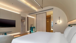 Ein modernes Hotelzimmer mit einem großen Bett, einem Flachbildfernseher, einem kleinen Tisch und einer blauen Akzentwand.