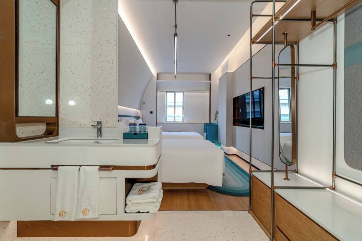 Una habitación de hotel moderna con una cama grande, un baño con tocador y un televisor montado en la pared.