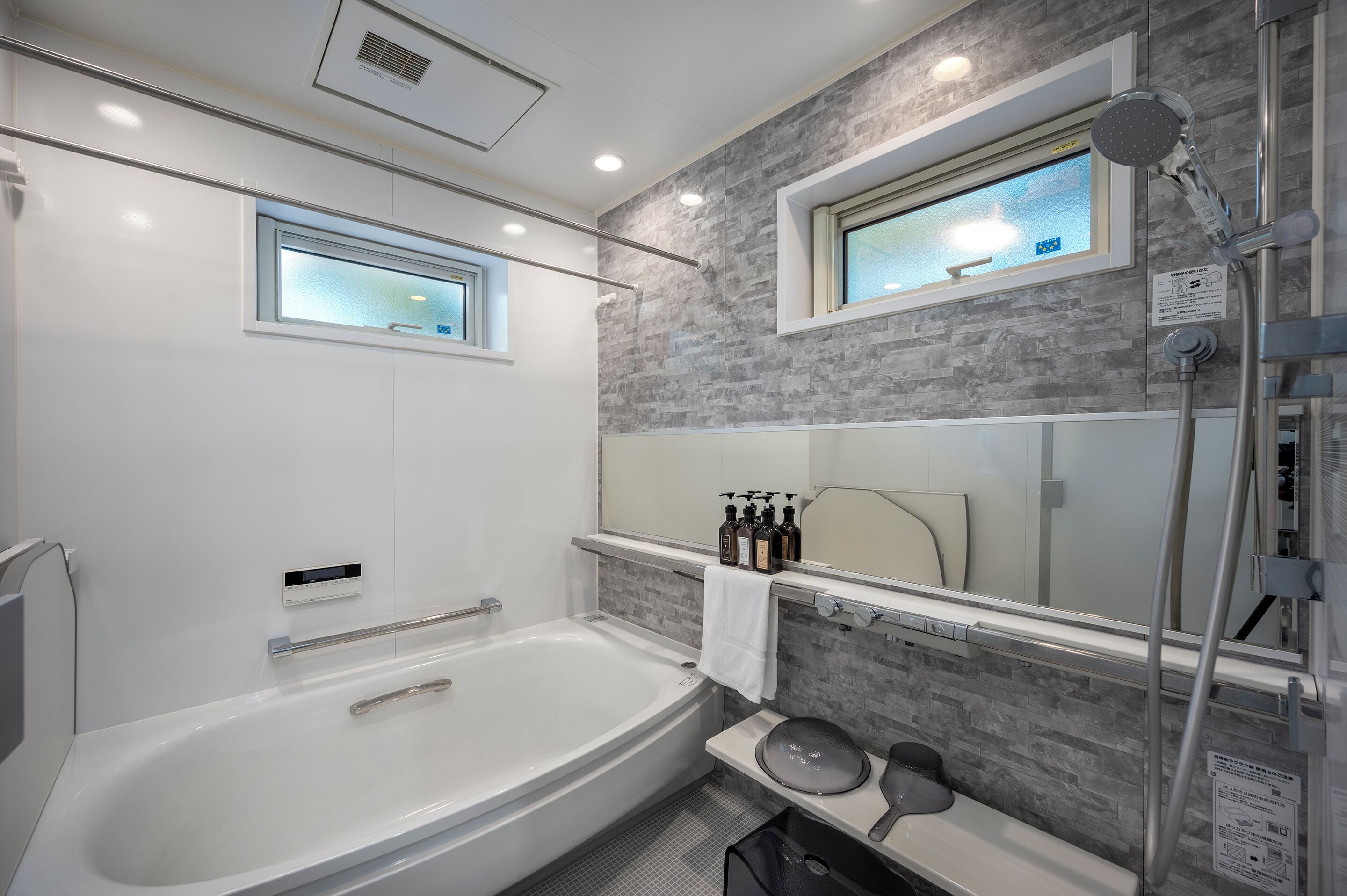 A modern bathroom with a bathtub, a shower, a vanity with a mirror, and a window.