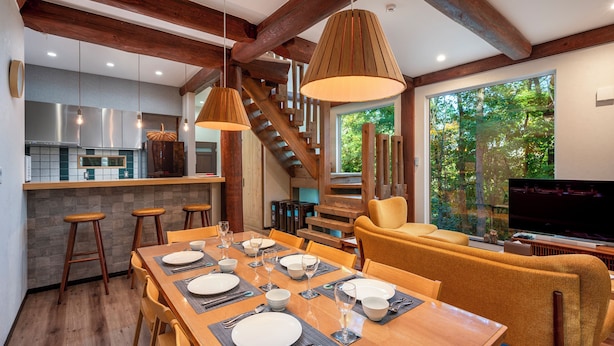 A modern kitchen with a central island, wooden beams, and a dining area with a table set for four. - Chise Fukuro by H2 Life (Furano)