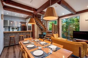 A modern kitchen with a central island, wooden beams, and a dining area with a table set for four. - Chise Fukuro by H2 Life (Furano)