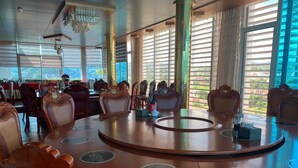 A conference room with a large oval table, multiple chairs, and large windows with blinds. - Duc Trung Hotel CB by Bayluxury (Thuc Phan)