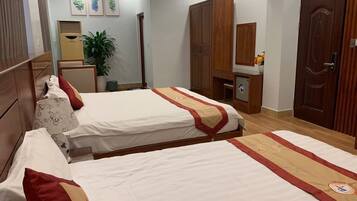 Una habitación de hotel con dos camas, un armario, un escritorio y una planta en maceta.