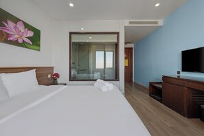 Een hotelkamer met een groot bed, een televisie, een houten dressoir en een douchecabine van glas.