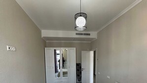 Une chambre avec un grand lit, une armoire et un miroir. Une porte donne accès à une autre pièce.
