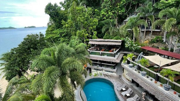 A pool surrounded by lush greenery and a beach, with a view of the sea. - Bugana Beach and Dive Resort (Sipalay)