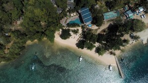 An aerial view of a coastal property with a beach, a swimming pool, and solar panels. - Bugana Beach and Dive Resort (Sipalay)