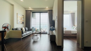 Un salon moderne avec un canapé, une table basse et un ventilateur. Il y a un balcon avec vue sur la ville.