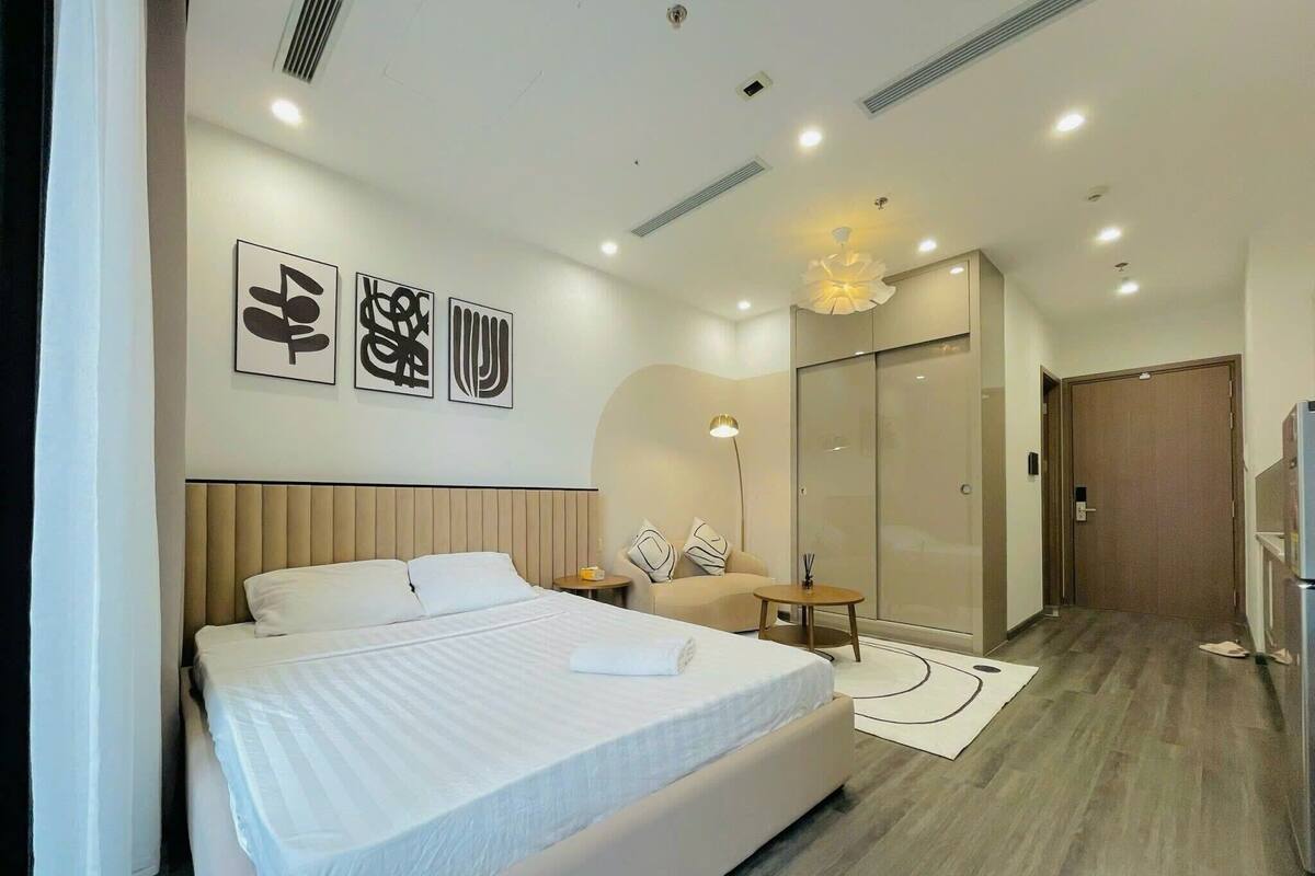 Una habitación de hotel moderna con una cama grande, un escritorio, una silla y un armario.