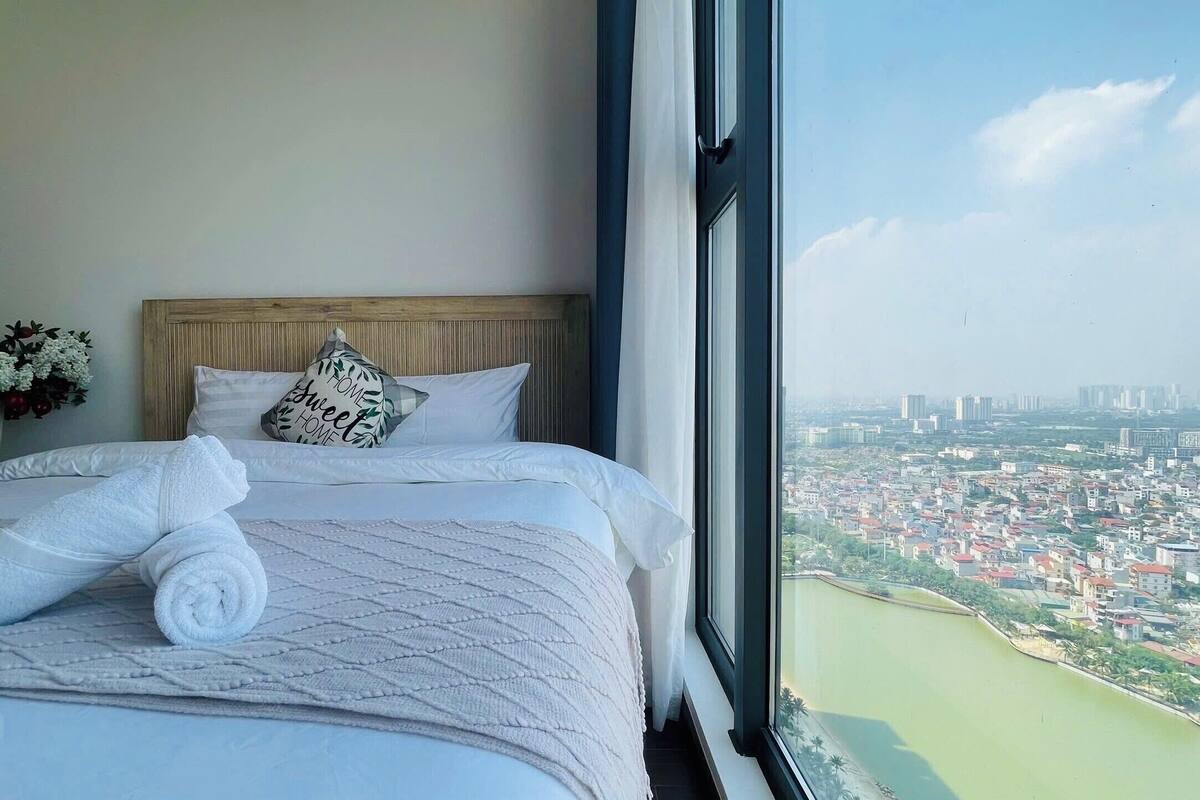 Habitación de hotel con una cama, vistas de la ciudad y un ventanal con vista al agua.
