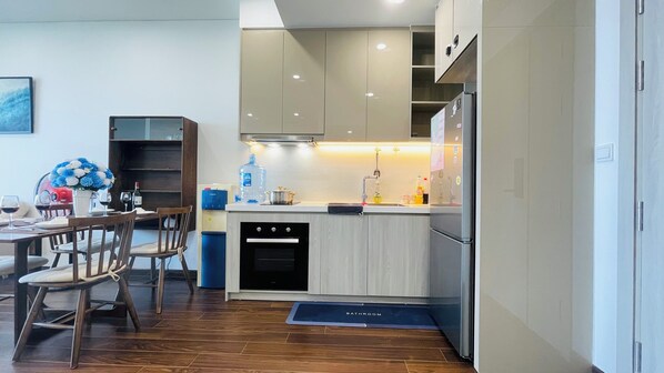 Una cocina moderna con comedor, que incluye una mesa de madera, sillas, dispensador de agua y refrigerador.